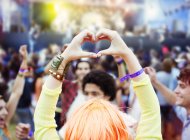 Жінка формує форму серця руками на музичному фестивалі — стокове фото