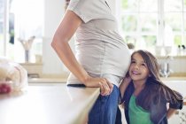 Chica escuchando a las madres embarazadas vientre - foto de stock