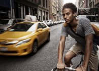 Young man riding bicycle on city street — Stock Photo