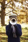 Хлопчик-підліток грає на трубі в осінній сільській місцевості — стокове фото