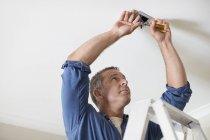 Skillful caucasian electrician working on ceiling lights — Stock Photo