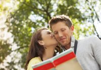 Woman kissing boyfriend in park — Stock Photo
