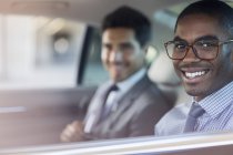 Hombres de negocios sonrientes sentados en coche - foto de stock