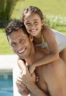 Father and daughter smiling by swimming pool — Stock Photo