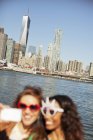 Women in novelty sunglasses taking picture by city cityscape — Stock Photo