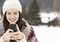 Close up of woman in knit hat text messaging with cell phone — Stock Photo