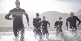 Triatleti fiduciosi e forti in mute che corrono a onde — Foto stock