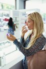Mulher cheirando perfume na farmácia — Fotografia de Stock
