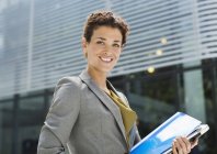 Happy businesswoman carrying folders outdoors — Stock Photo