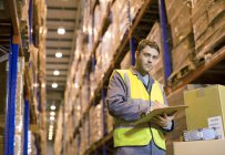 Worker writing on clipboard in warehouse — Stock Photo