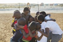 African boys huddled together in dirt field — Stock Photo