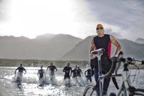 Triathletes emerging from water — Stock Photo