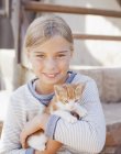 Retrato de niña sonriente sosteniendo gatito - foto de stock