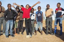Chicos africanos animando juntos en el campo de tierra - foto de stock