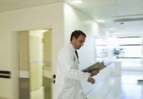 Doctor reading medical chart in hospital hallway — Stock Photo