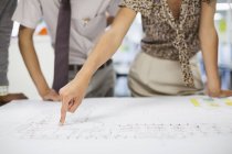 Cropped image of business people reading blueprints in meeting — Stock Photo