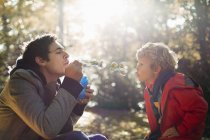 Father and son blowing bubbles in park — Stock Photo