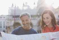 Улыбающаяся пара смотрит на карту Венеции — стоковое фото