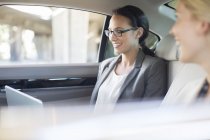 Businesswomen working in car back seat — Stock Photo