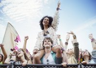 Весела жінка на чоловічих плечах на музичному фестивалі — стокове фото