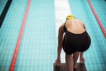 Swimmer poised at starting block above pool — Stock Photo