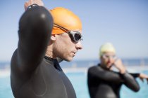 Confident and strong triathlete tying on goggles outdoors — Stock Photo