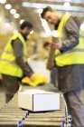 Trabalhadores que verificam as embalagens na correia transportadora no armazém — Fotografia de Stock
