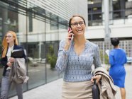Бізнес-леді розмовляють на мобільному телефоні поза офісною будівлею — стокове фото