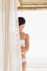 Frau in BH und Unterwäsche hinter Vorhang — Stockfoto