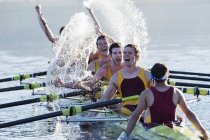Rowing team splashing and celebrating in scull on lake — Stock Photo
