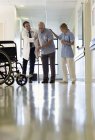 Doctor and nurse helping older patient walk in hospital — Stock Photo