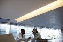 Бізнесмен і бізнес-леді обговорюють документи в сучасному офісі — стокове фото