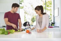 Dog with couple cooking in kitchen at modern home — Stock Photo