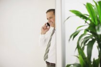 Бизнесмен разговаривает по мобильному телефону в современном офисе — стоковое фото