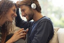 Молода приваблива пара слухає навушники на дивані — стокове фото