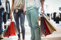 Couple carrying shopping bags in clothing store — Stock Photo