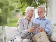 Couple utilisant la tablette numérique ensemble sur la balançoire porche — Photo de stock