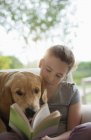 Menina lendo com cão em poltrona em casa moderna — Fotografia de Stock