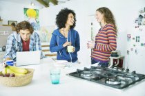 Jóvenes amigos felices relajarse juntos en la cocina - foto de stock