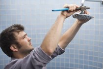 Умелый кавказский сантехник работает на душевой головке в ванной комнате — стоковое фото