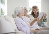 Ältere kaukasische Frauen mit digitalem Tablet auf dem Sofa — Stockfoto