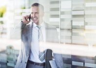 Бизнесмен разговаривает по мобильному телефону в современном офисе — стоковое фото