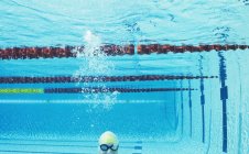 Nadador sonriendo bajo el agua en la piscina - foto de stock