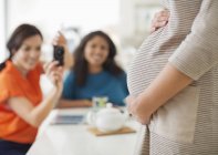 Mujer tomando fotos del vientre de una amiga embarazada - foto de stock