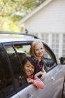 Girls smiling out car window — Stock Photo