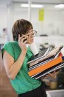 Businesswoman with folders talking on cell phone — Stock Photo