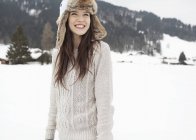 Mulher feliz usando chapéu de pele no campo nevado — Fotografia de Stock