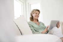 Seniorin nutzt digitales Tablet auf Sofa — Stockfoto