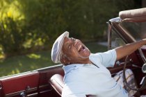 Смеющийся пожилой мужчина за рулем кабриолета — стоковое фото