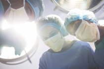 Surgeons bent over patient in operating room — Stock Photo